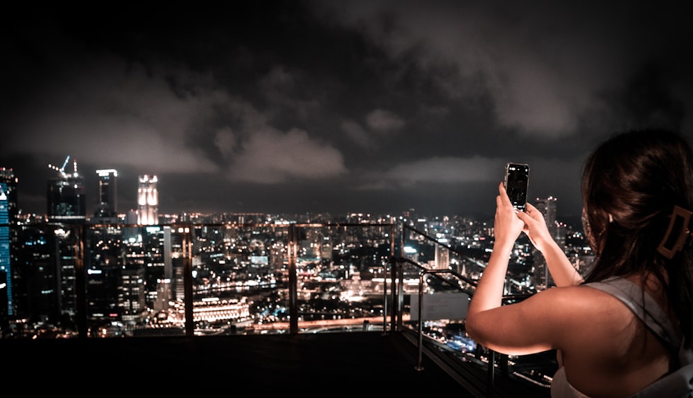 person taking photo of city skyline during night time
