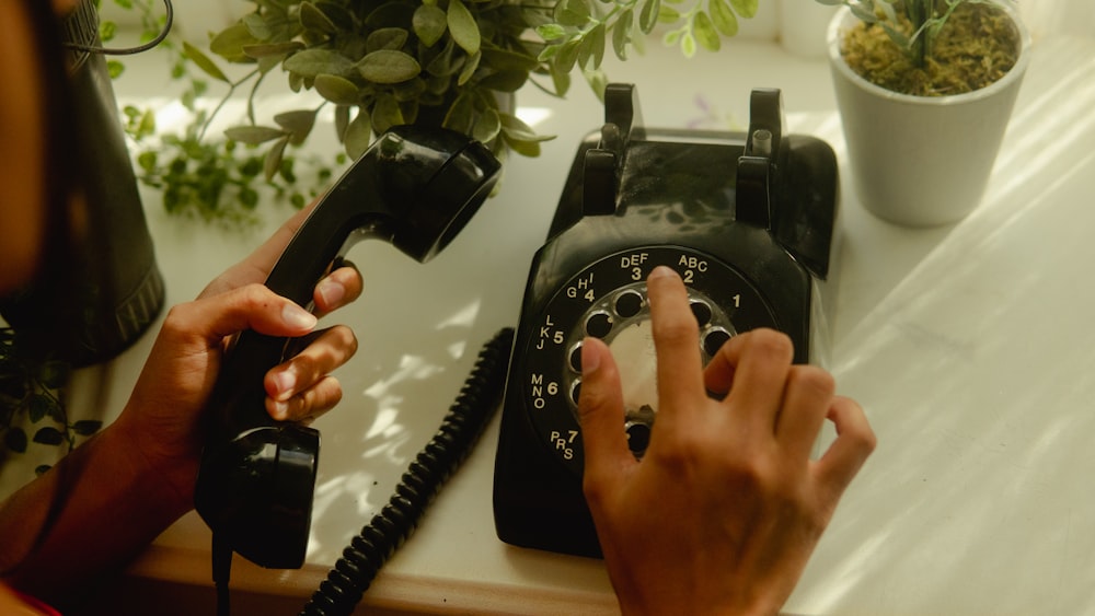 person holding black rotary telephone