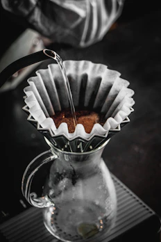 Elegant pour-over coffee setup with steaming hot coffee dripping into a glass carafe.