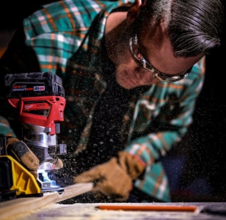 man in green and black plaid long sleeve shirt holding red and black cordless hand drill