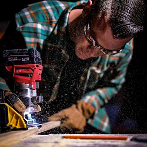 man in green and black plaid long sleeve shirt holding red and black cordless hand drill