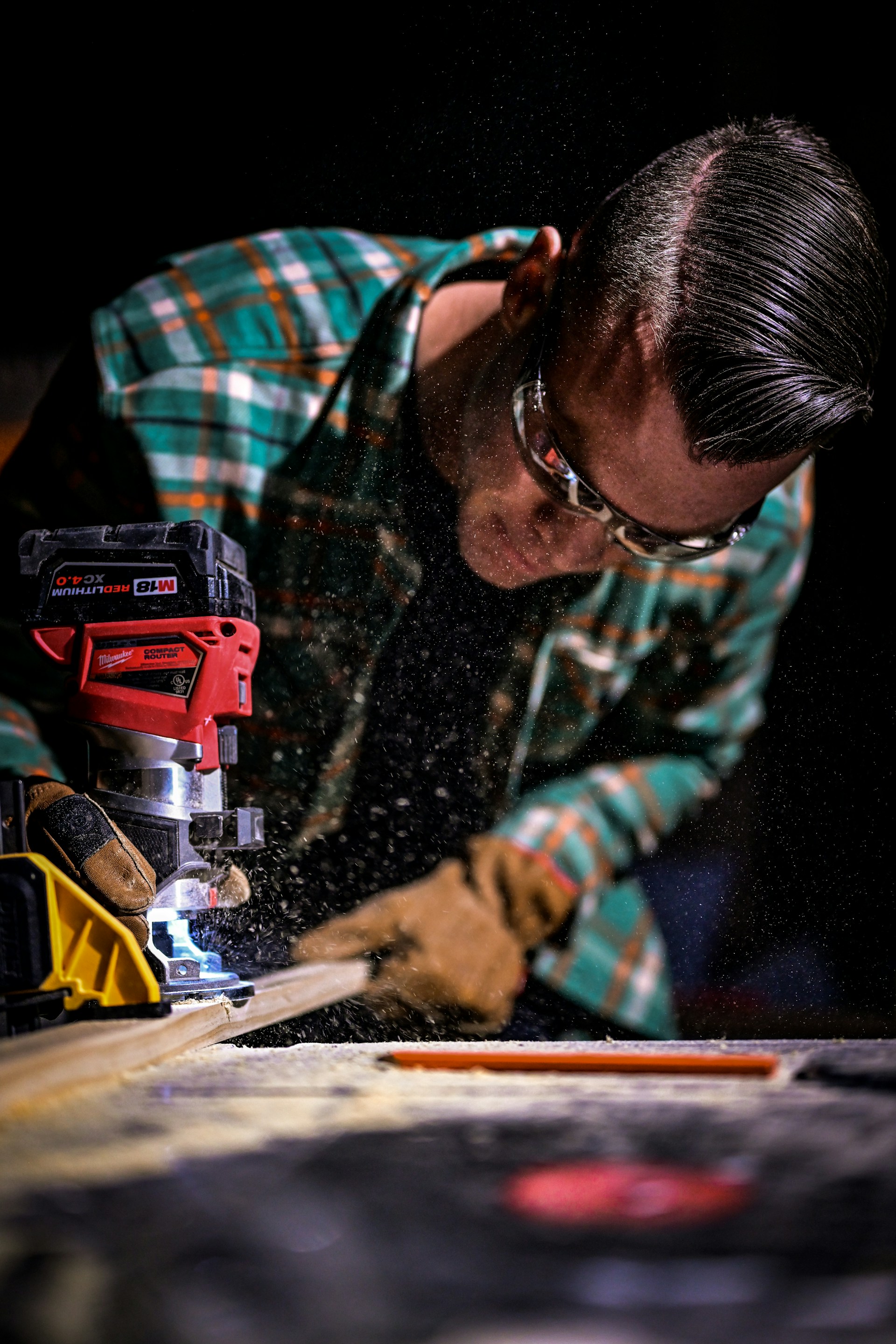 man in green and black plaid long sleeve shirt holding red and black cordless hand drill