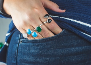 person wearing silver teal and green gemstone ring