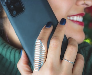 woman wearing silver ring holding black smartphone