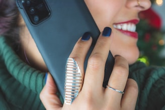 woman wearing silver ring holding black smartphone