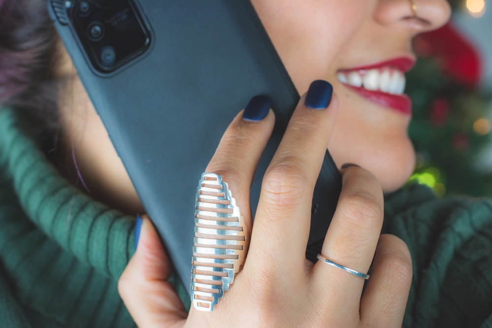woman wearing silver ring holding black smartphone