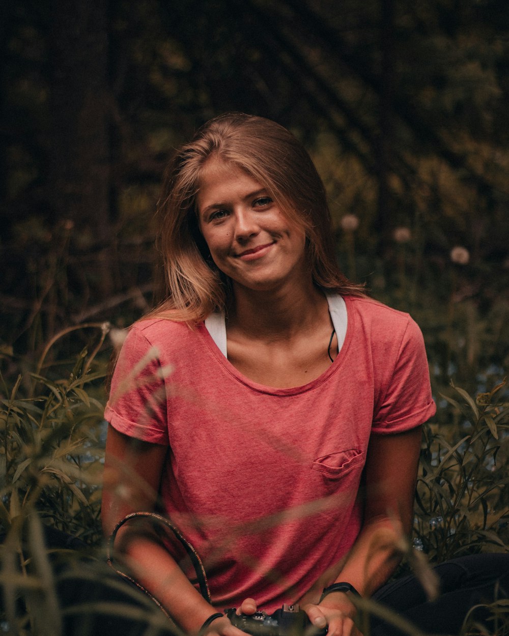 Frau in rosa U-Ausschnitt-T-Shirt sitzt auf Rasenplatz