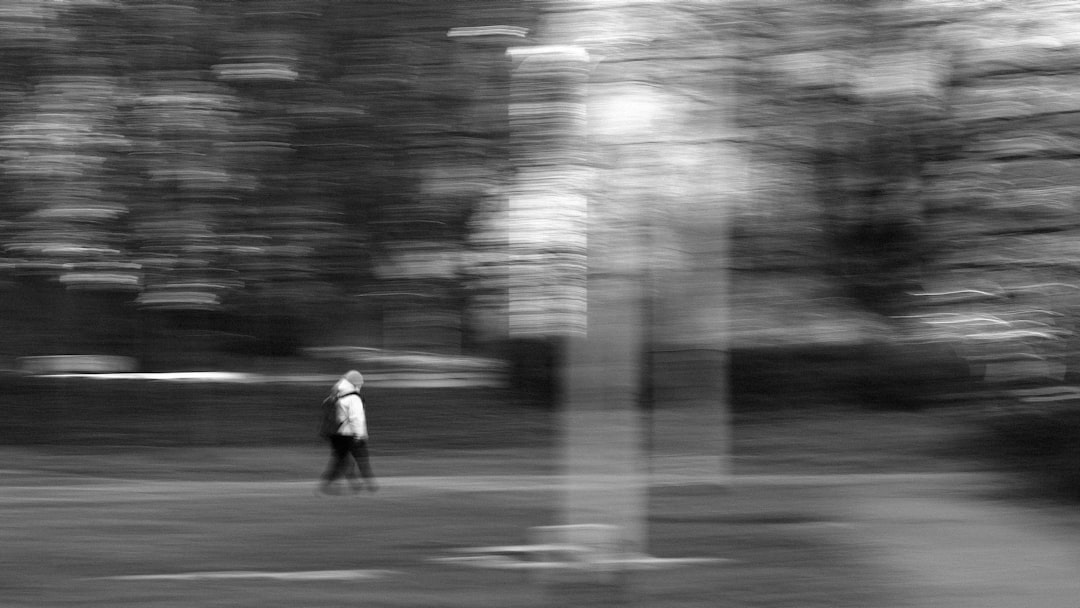 grayscale photo of man walking on road