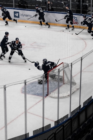 Coach Dave demonstrating stick handling drills on the rink with focused players watching.