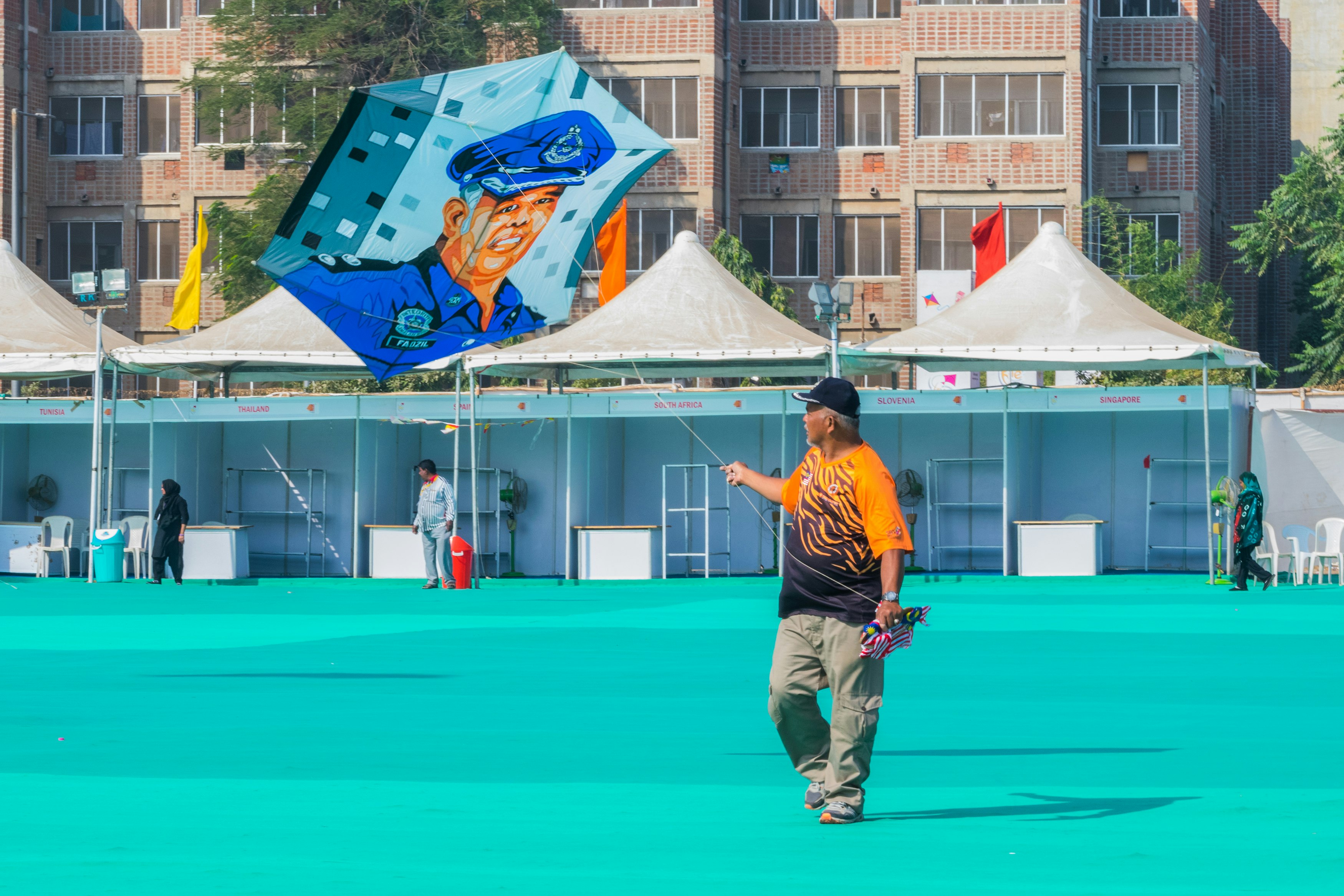 man in orange shirt and brown pants holding blue umbrella