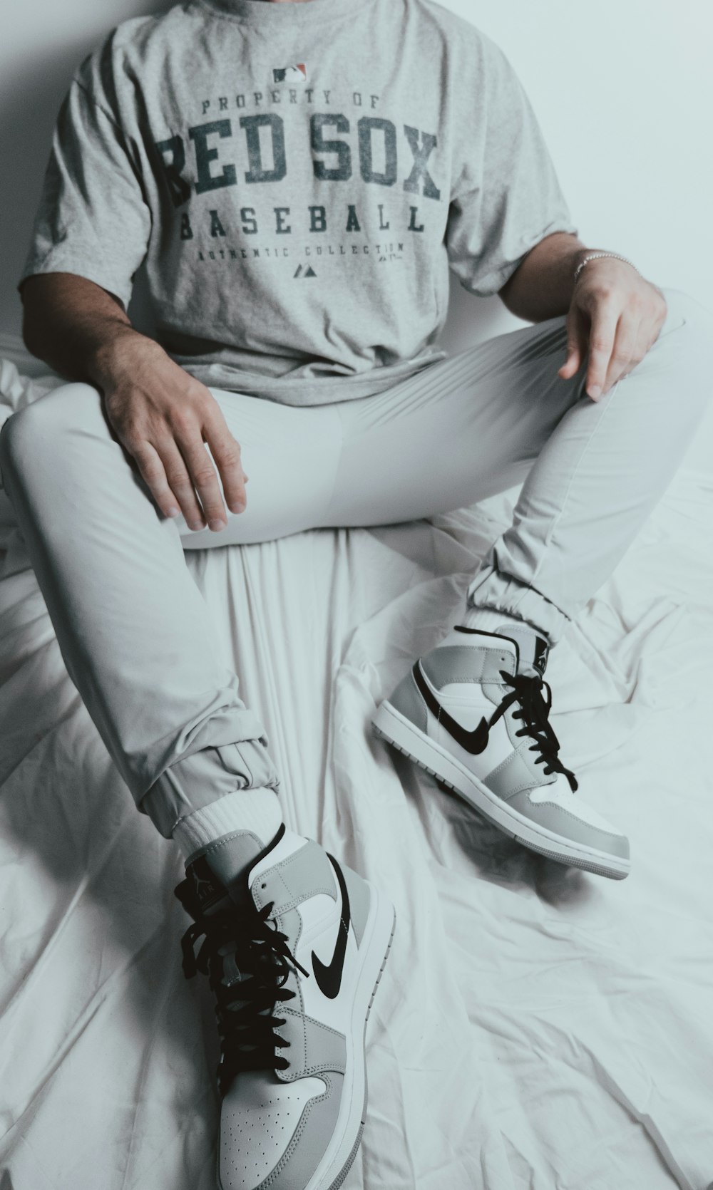 person in gray shirt and white pants wearing black and white nike sneakers