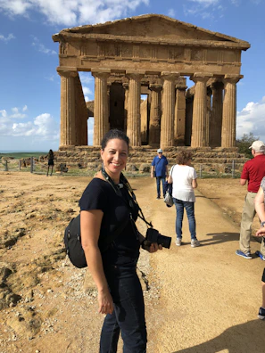 A solo traveler taking a photo in front of a famous ancient temple, full of wonder.