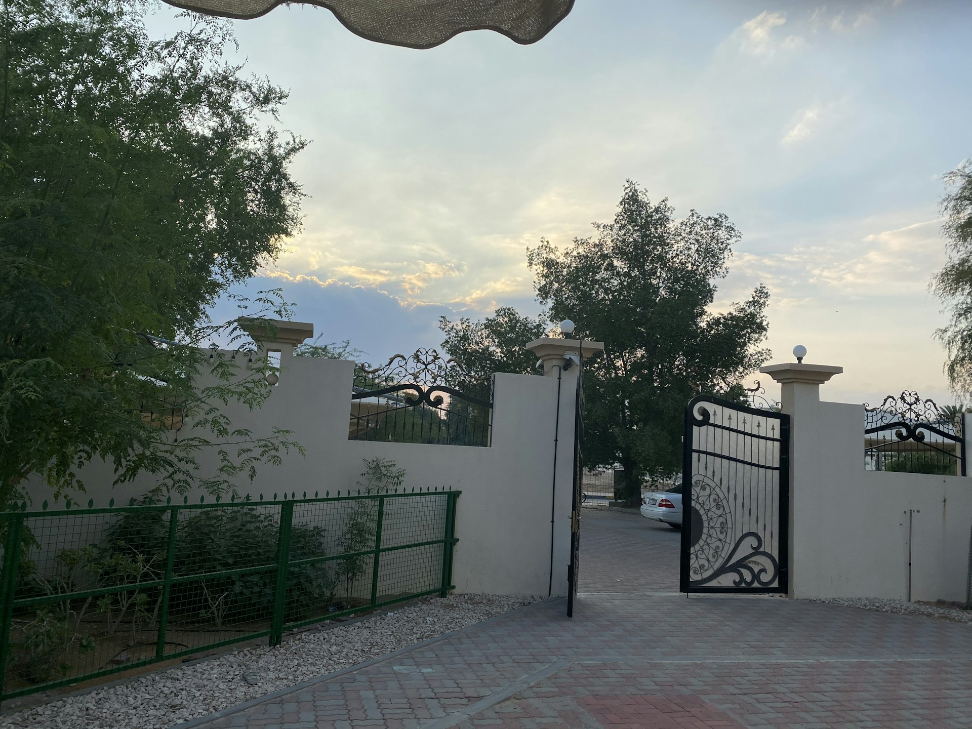 Wide shot of a grand dark blue gate standing tall against a serene evening sky.