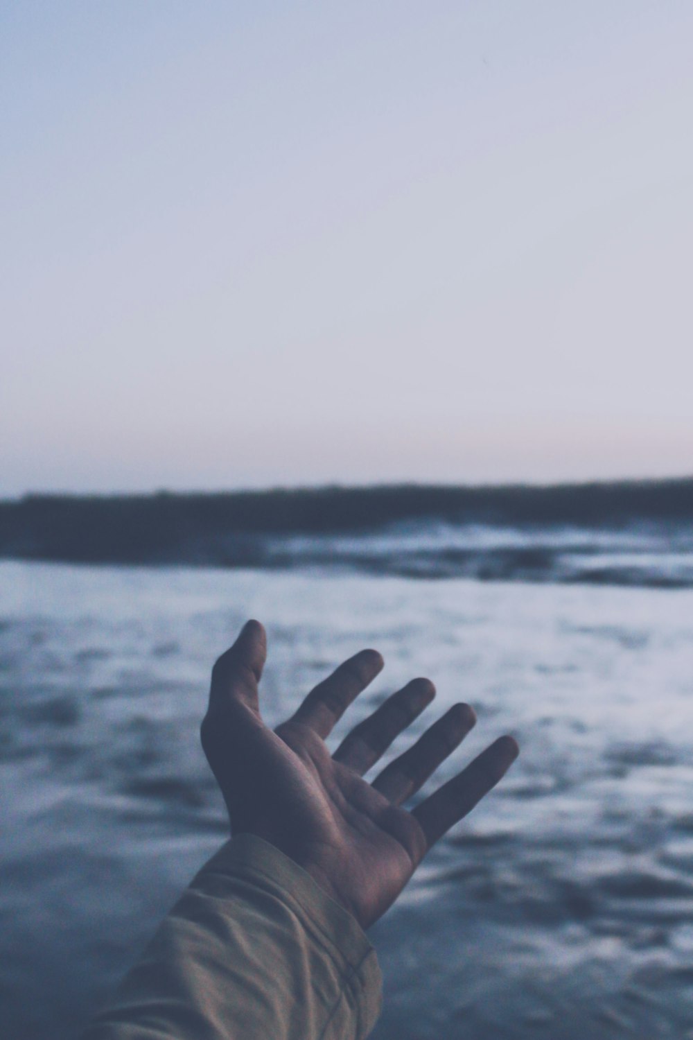 mano de las personas cerca del cuerpo de agua durante el día