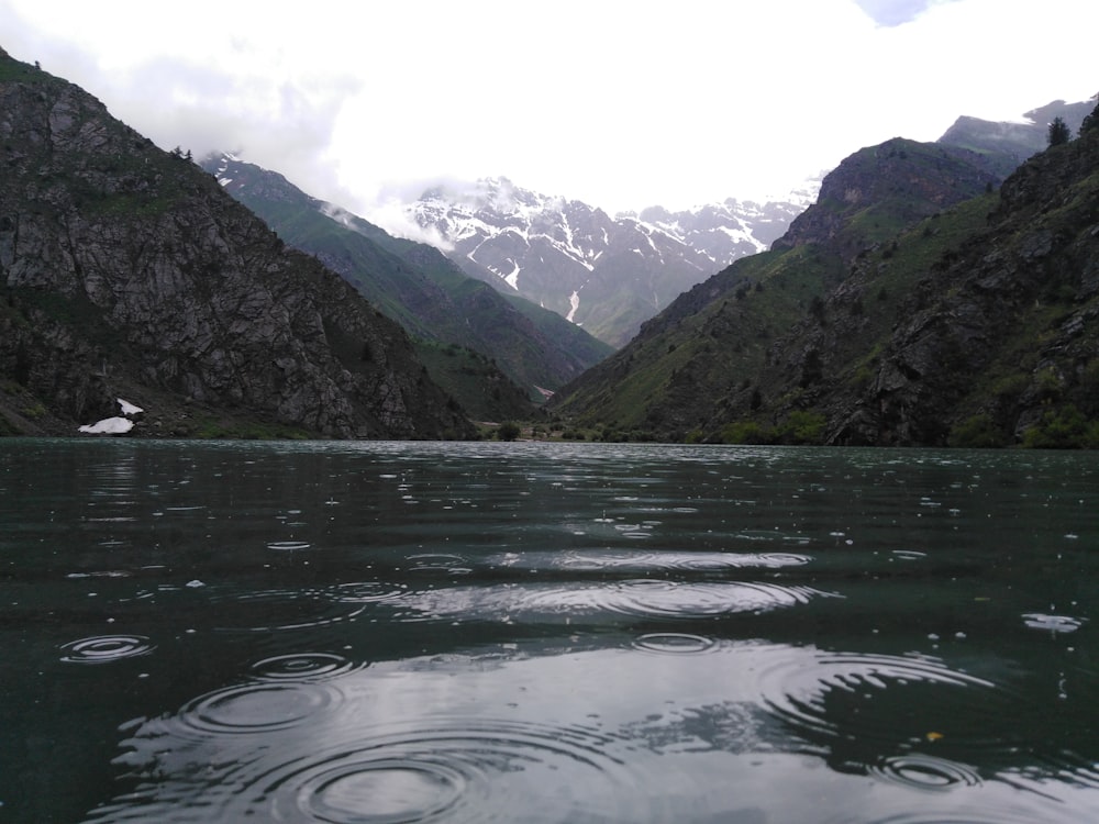 body of water near green mountain during daytime