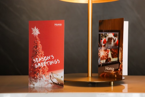 A close-up shot of a holiday greeting card with thick embossed text and a shimmering gold cover.