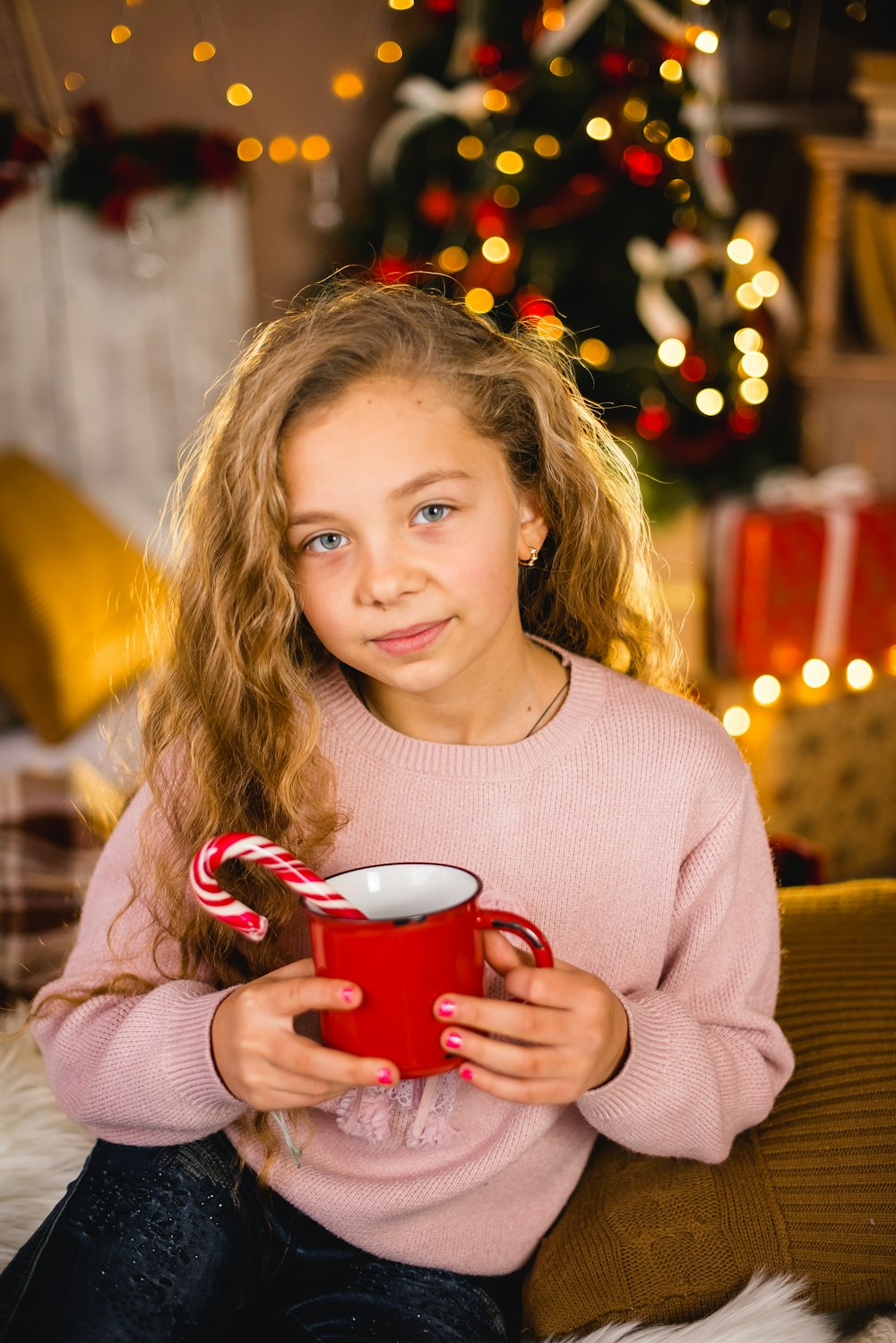 girl in beige sweater holding red ceramic mug