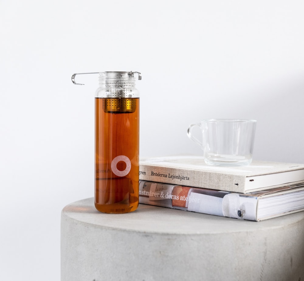 Encendedor desechable naranja y plateado junto a un vaso transparente