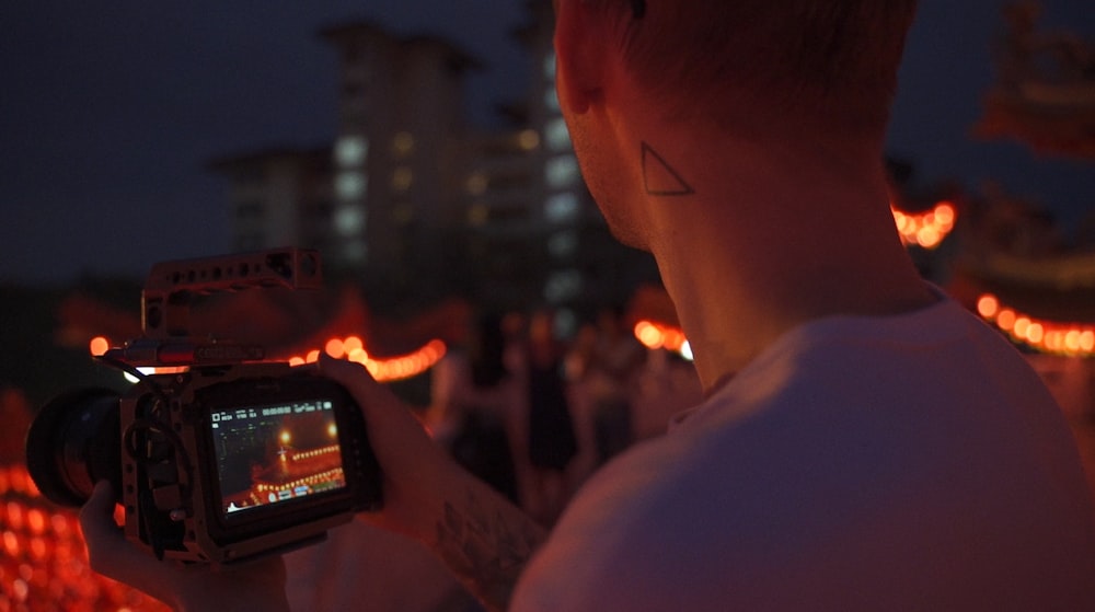 man in white shirt holding black smartphone