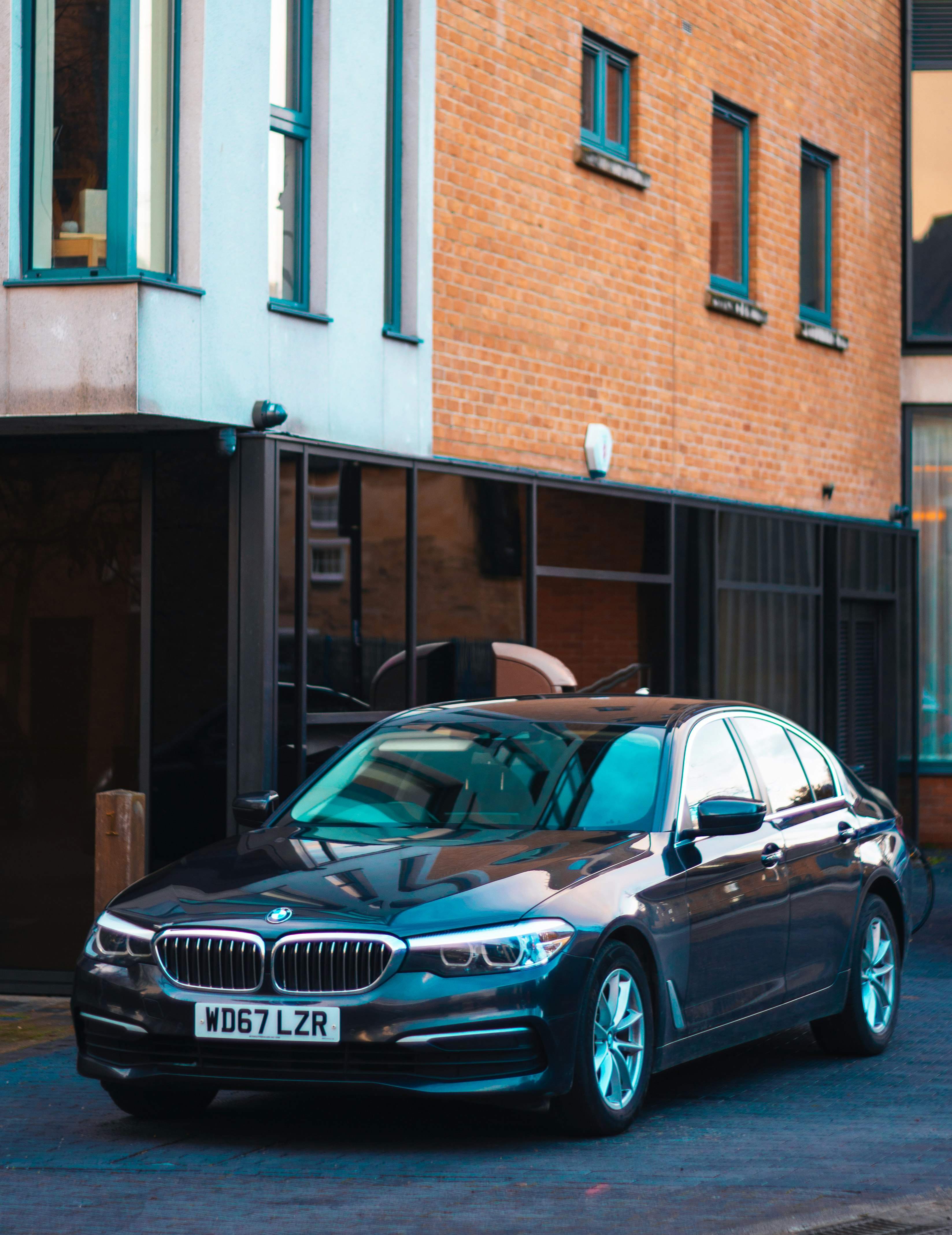 black mercedes benz sedan parked beside brown concrete building during daytime