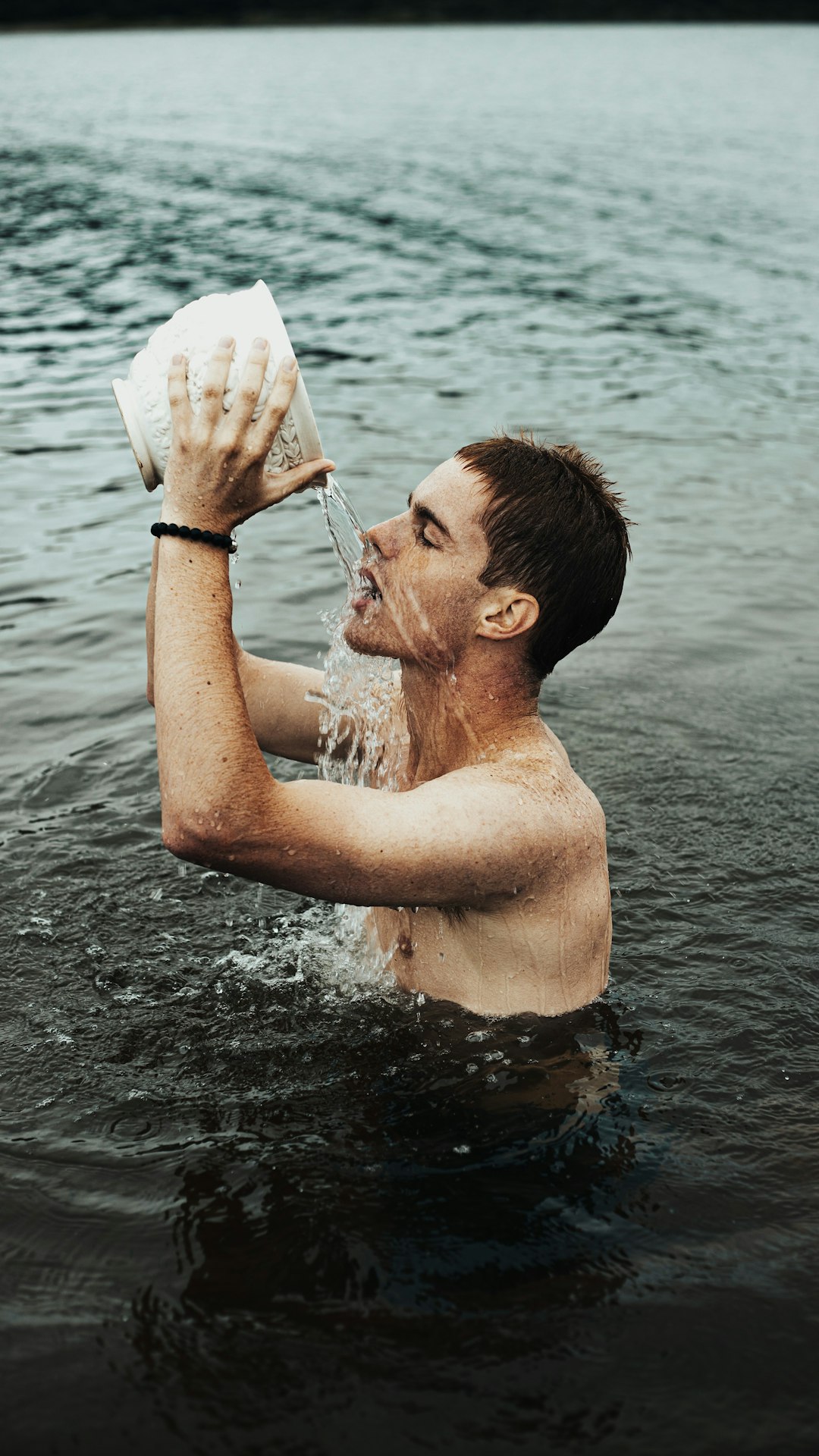 man in water holding white plastic bag