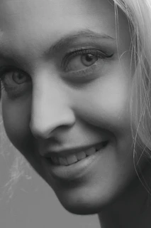 A close-up of a woman smiling, showcasing a fresh, stylish haircut that highlights her facial features.