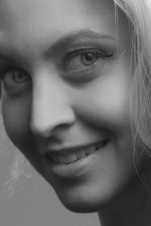 A close-up of a woman smiling, showcasing a fresh, stylish haircut that highlights her facial features.