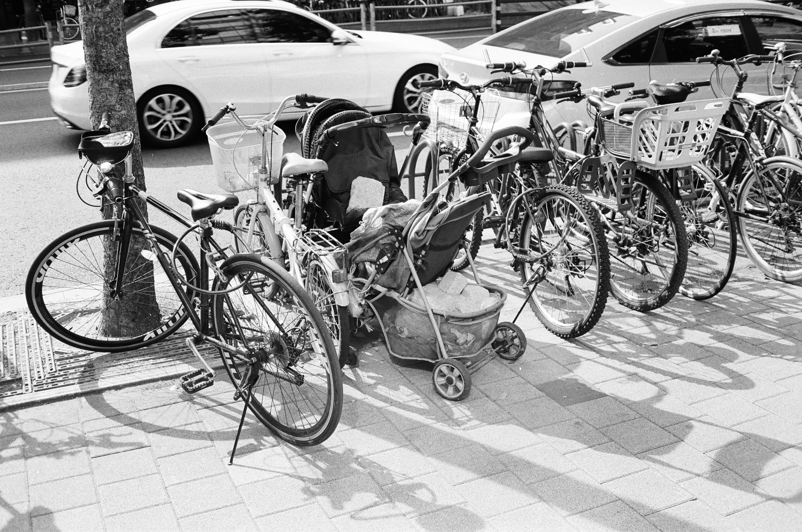 Grå barnvagn parkerad på en solig gångväg i en park
