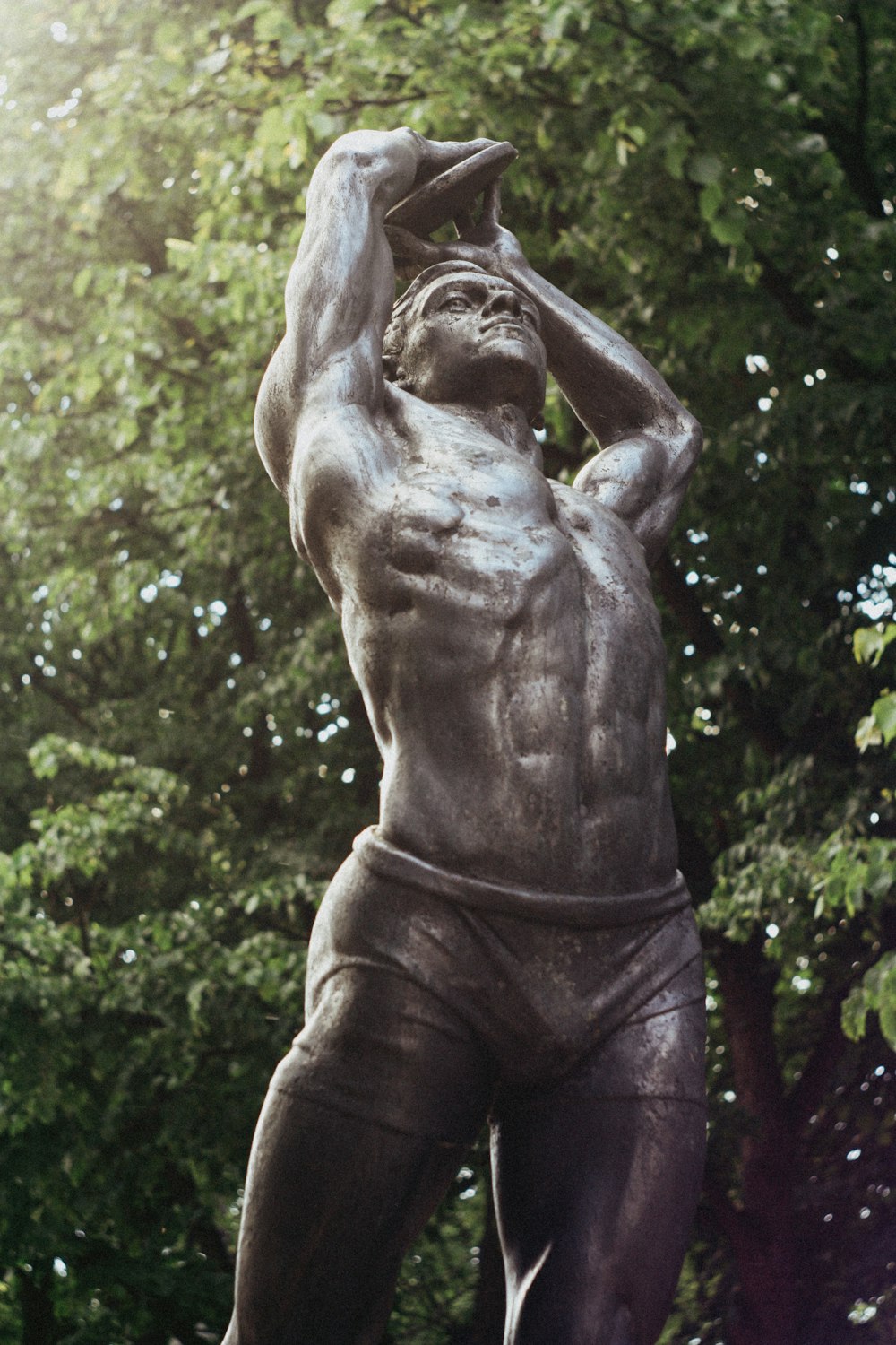 brown statue of man near green trees during daytime