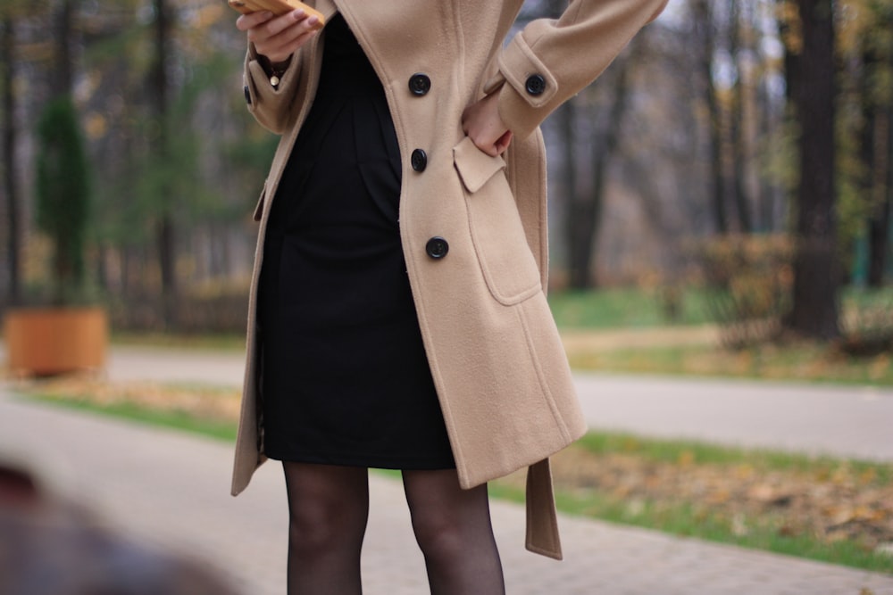 낮 동안 길에 서 있는 갈색 코트를 입은 여자