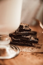Close-up of rich, handmade dark chocolate bars stacked on a rustic wooden table.