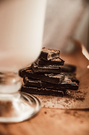 Close-up of rich, glossy 100% cacao chocolate bars stacked neatly on a rustic wooden table.