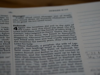 A close-up view of a page from a book, likely the Bible, featuring text in both regular and bolded font. The bolded section highlights the title 'Deborah,' followed by numbered verses. The surrounding text includes both narrative content and chapter and verse numbers.