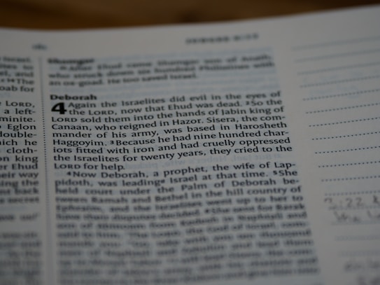 A close-up view of a page from a book, likely the Bible, featuring text in both regular and bolded font. The bolded section highlights the title 'Deborah,' followed by numbered verses. The surrounding text includes both narrative content and chapter and verse numbers.
