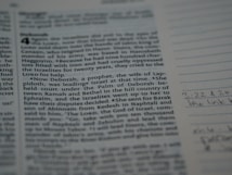 A close-up image of a page from a book, possibly a religious text, with a passage about Deborah. The left side displays text while the right margin contains handwritten notes and line markings on the lines. The text is clear, and the image is slightly dimly lit.