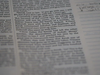 Close-up of a hand writing notes beside an open book with historical sketches.