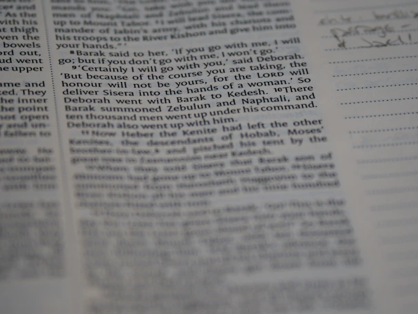 Close-up of a hand writing notes beside an open book with historical sketches.