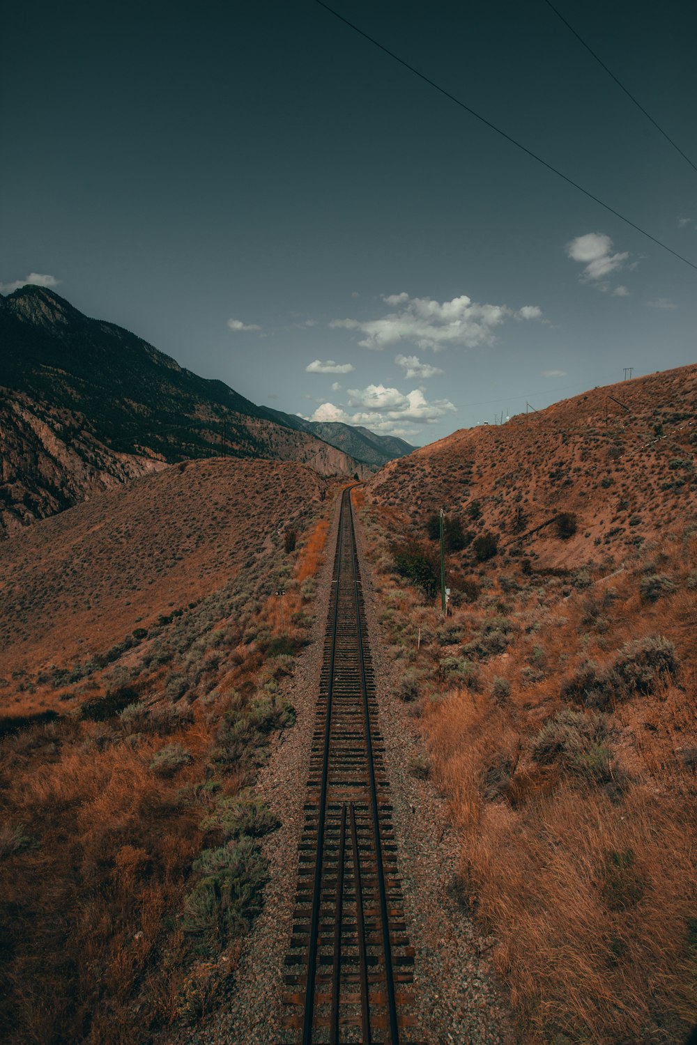 Carril de tren de metal negro entre el campo de hierba marrón durante el día