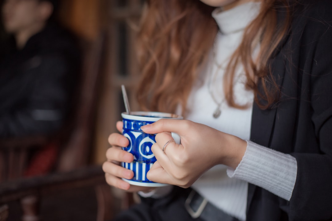 woman in white long sleeve shirt holding blue ceramic mug