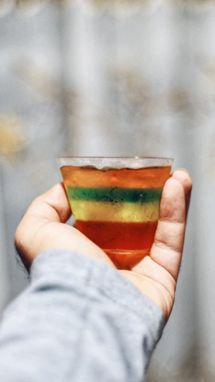 Close-up of colorful liquid gelatins in transparent cups, highlighting their smooth texture.