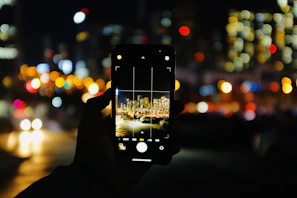 Close-up of a sleek smartphone displaying a vibrant cityscape at night