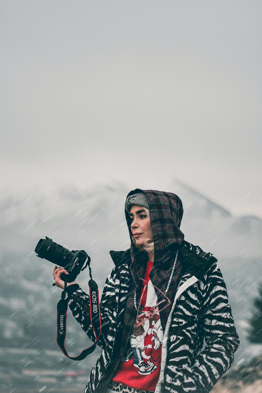 woman in black and white jacket holding black dslr camera