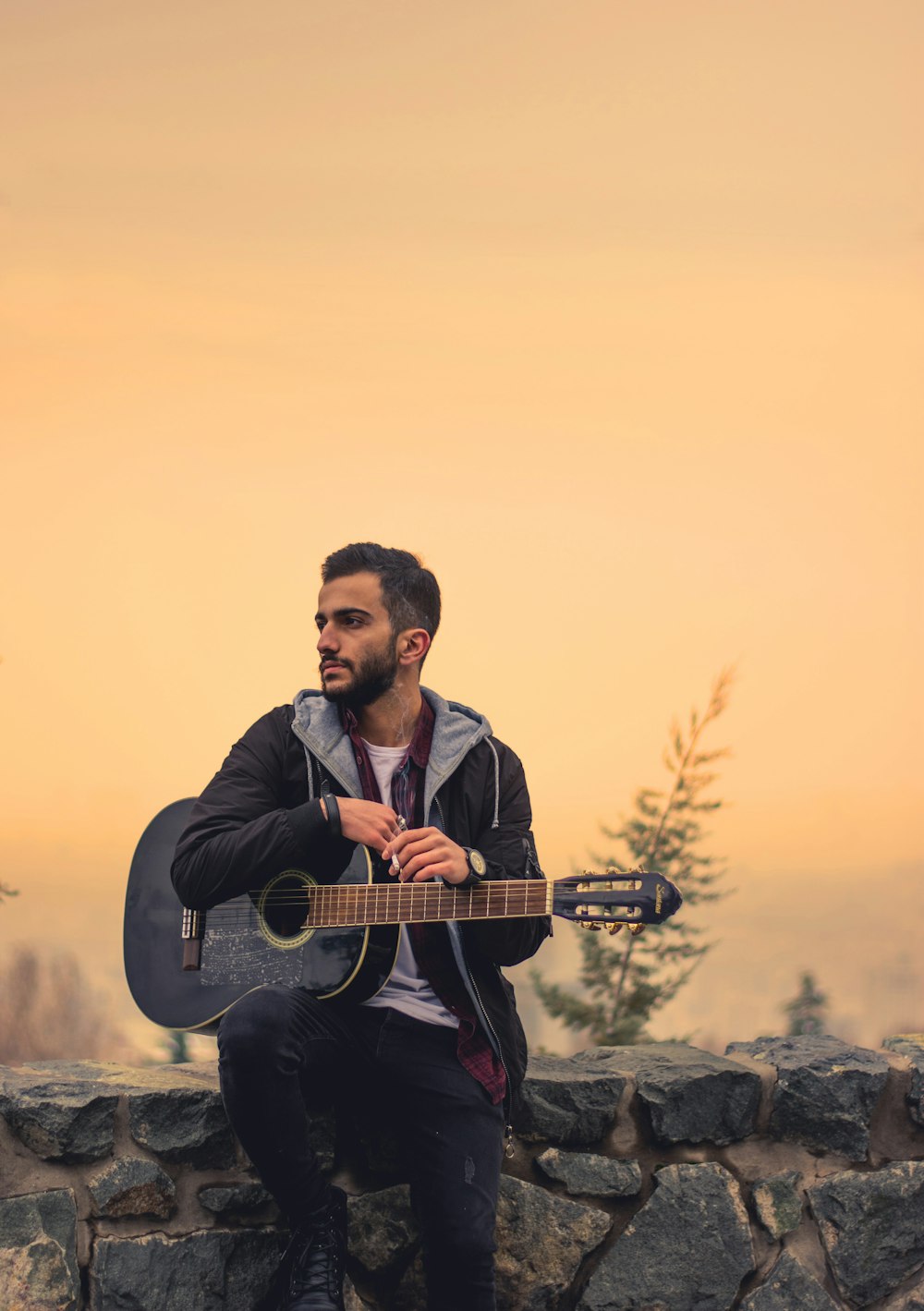 man in black jacket playing guitar