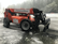 Large orange forklift-style construction vehicle with 'EquipmentShare' branding, parked on a wet and slightly snowy surface, surrounded by a misty forest and power lines in the background.