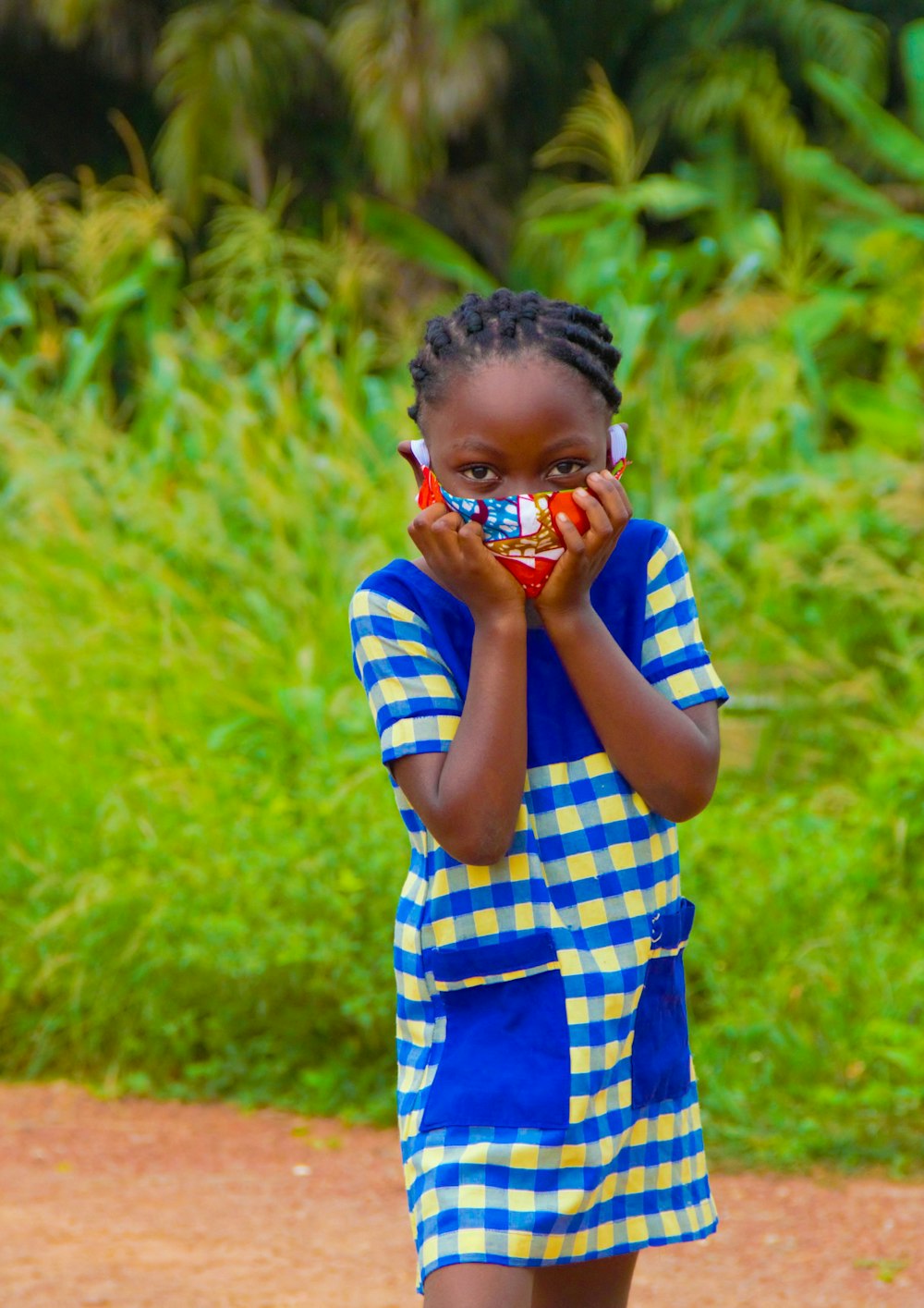 boy in blue and white checked shirt covering his face with his hand