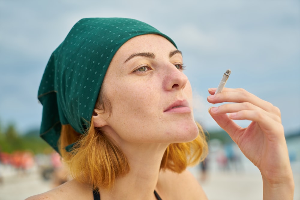 青いニット帽をかぶった女性がタバコを吸う