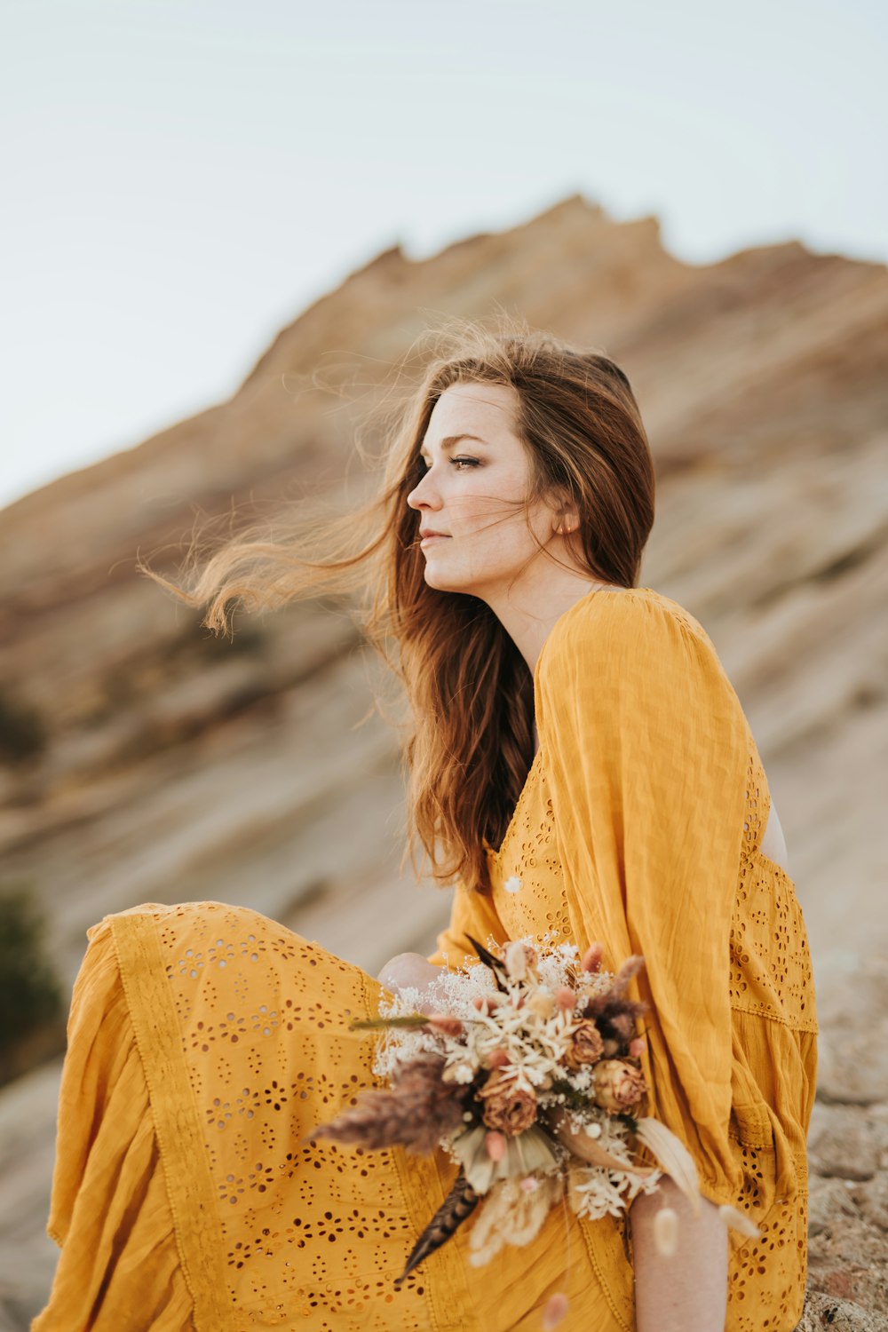 woman in yellow long sleeve shirt holding white flowers