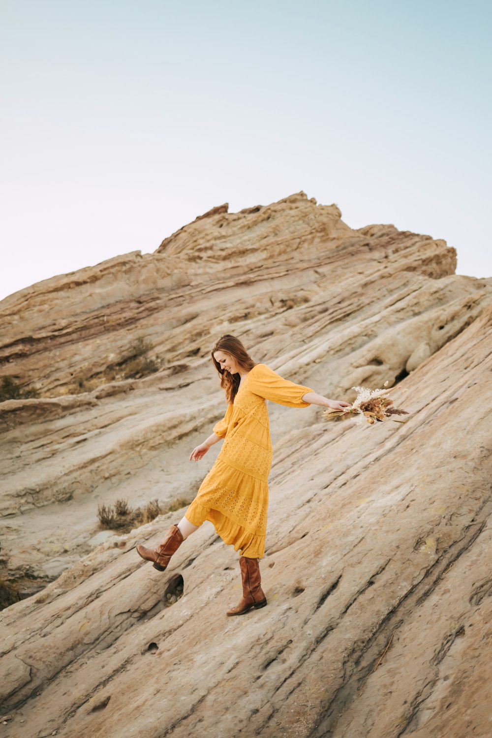 woman in orange dress standing on brown rock formation during daytime