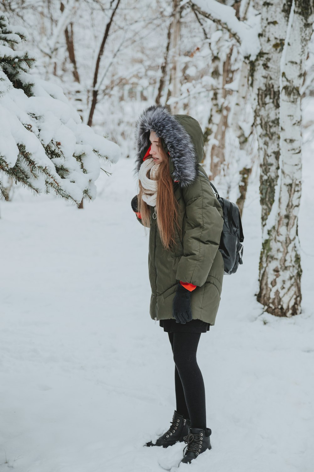 woman in gray jacket standing on snow covered ground during daytime
