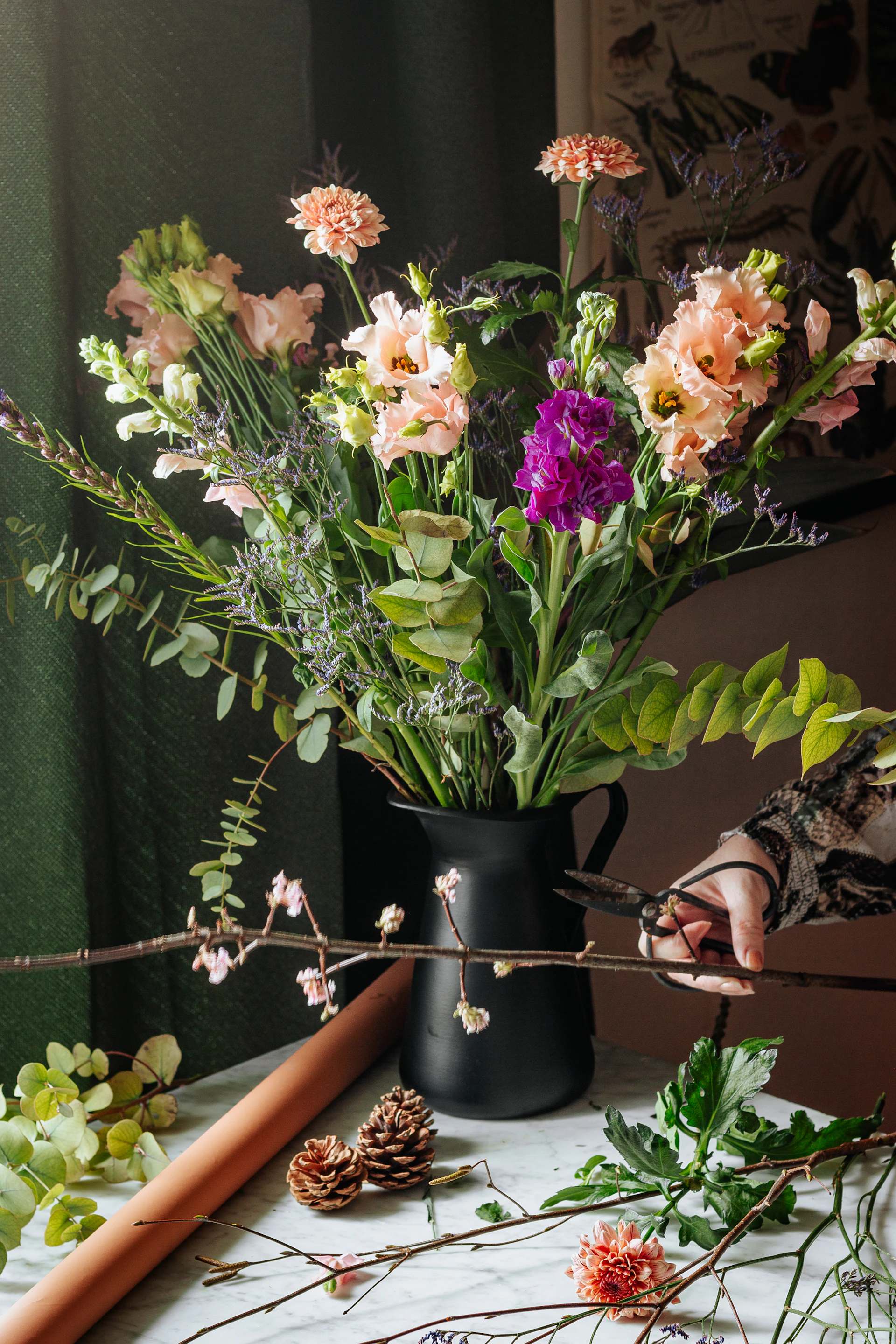 A tall seasonal arrangement of garden flowers against a deep green backdrop